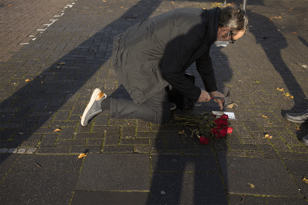 Ein Mann kniet nieder, um im Rahmen einer Gedenkzeremonie im November einen Strauß Rosen zu schneiden.