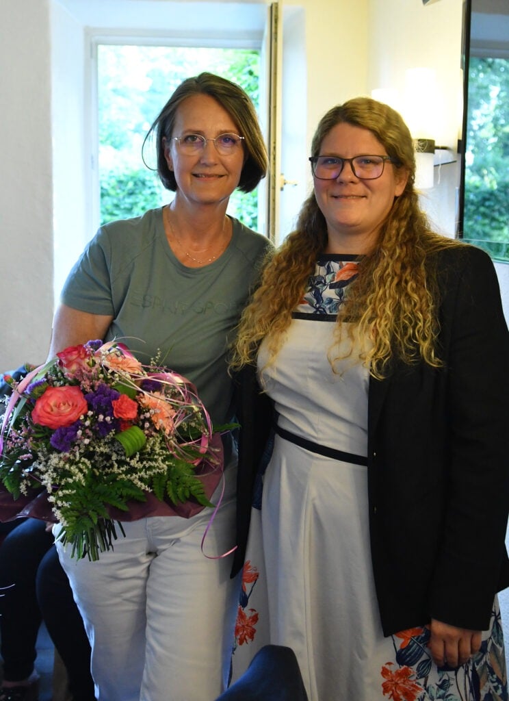 Sylvia Czakalla, die Damenpräsidentin, steht neben einer anderen Frau, die Blumen hält.