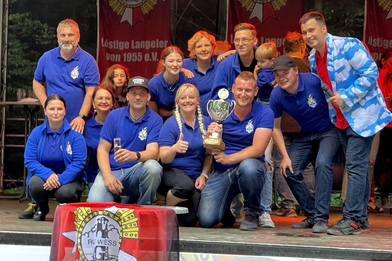 Eine Gruppe von Menschen posiert auf einer Bühne beim Wiesenfest für ein Foto.