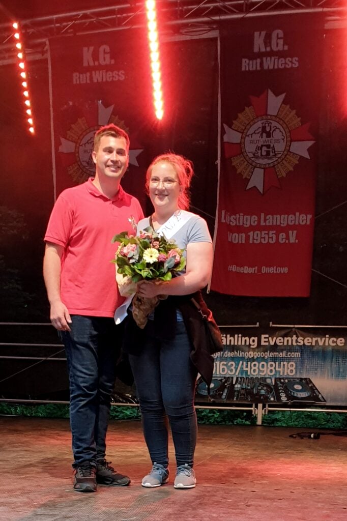 Ein Mann und eine Frau stehen mit Blumen auf der Bühne beim lösenden Wiesenfest.