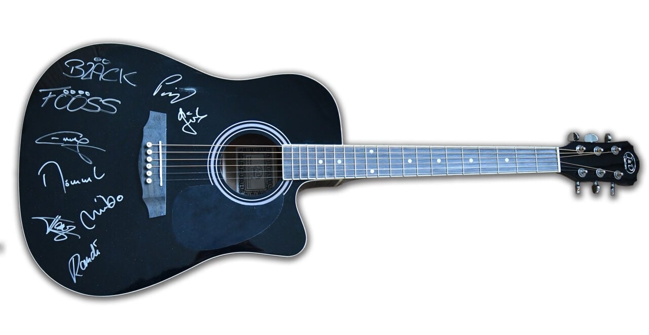 Eine schwarze Akustikgitarre mit Signaturen darauf, zur Versteigerung bei einer Benefizveranstaltung.