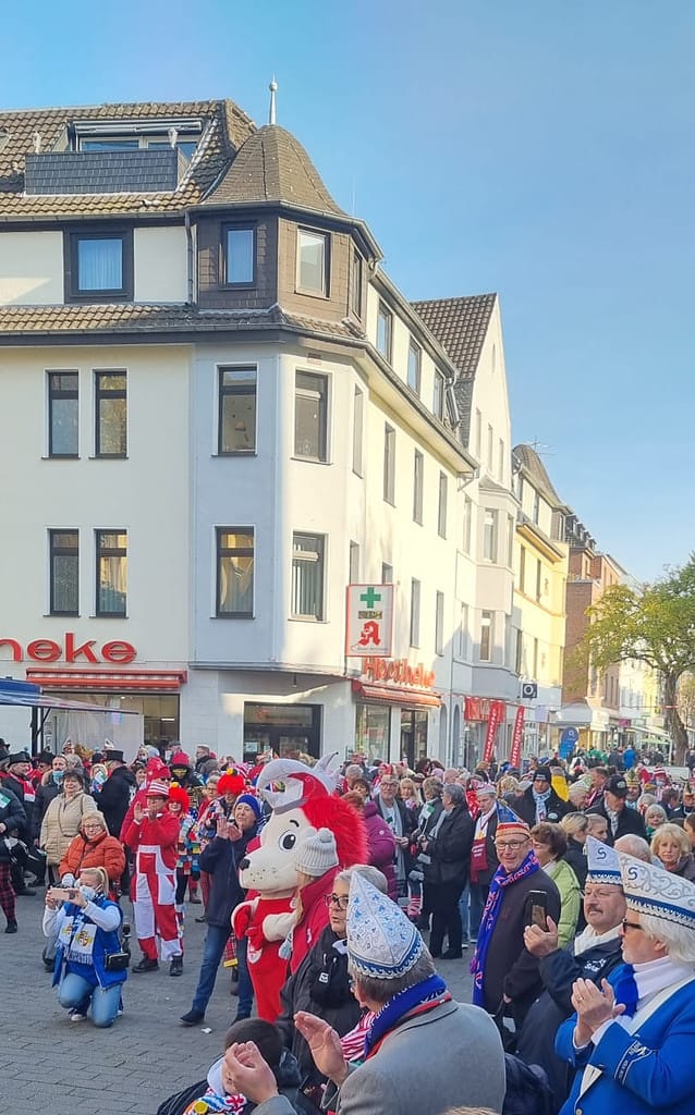 Eine Gruppe von Menschen mit Weihnachtsmützen auf einer Straße feiert die Eröffnung.