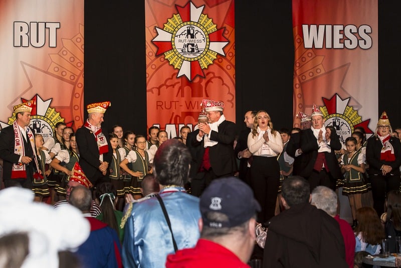 Eine Gruppe von Menschen steht während der Rückblick- oder Sessionseröffnung in der Jakob-Engelshalle auf der Bühne vor einem Banner.
